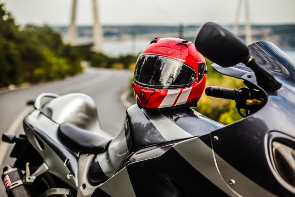 black motorcycle and red helmet on it, the road and trees behind