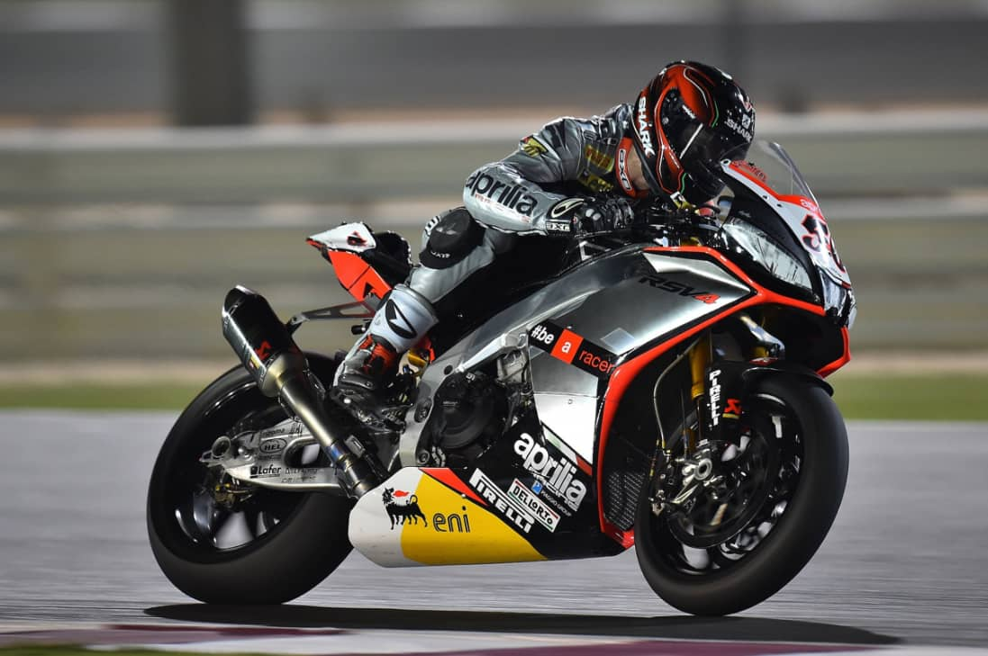 A motorcycle racer leaning into a turn on a race track at night